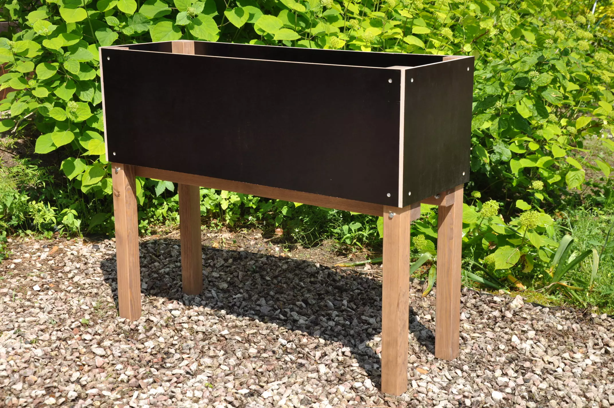 Luxe zwarte moestuinbak op poten smal model 90x32cm in een natuurlijke tuinsetting